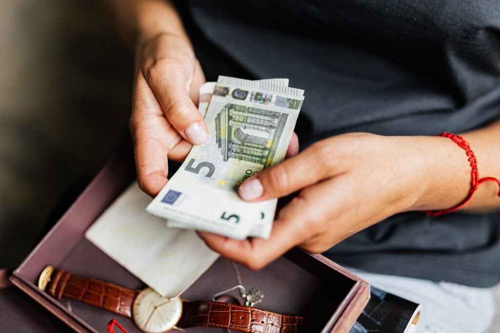 Manos contando billetes de 5 euros sobre una caja