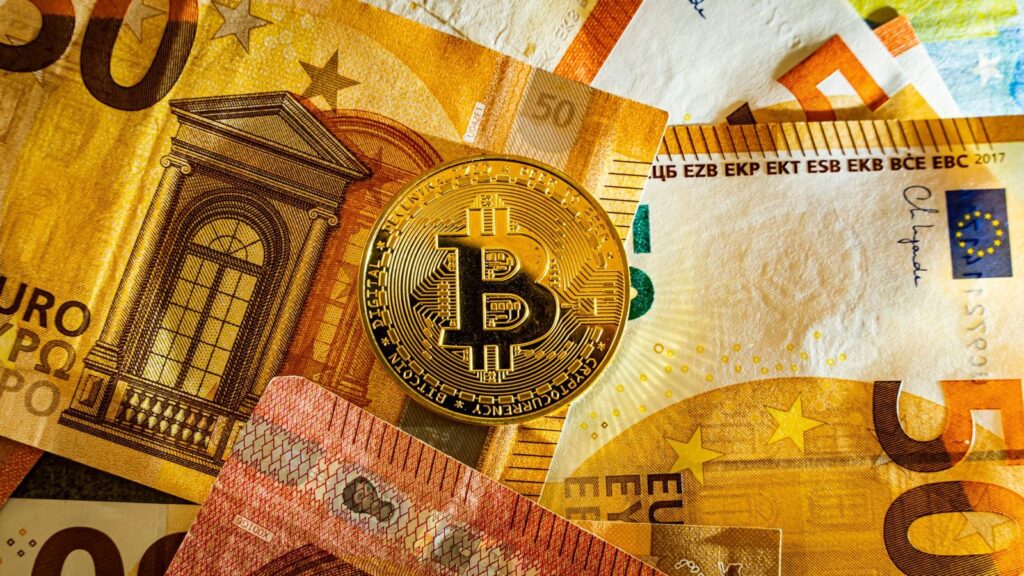 Moneda de bitcoin sobre billetes de 50 euros: vender bitcoin en un cajero y cobrar en efectivo