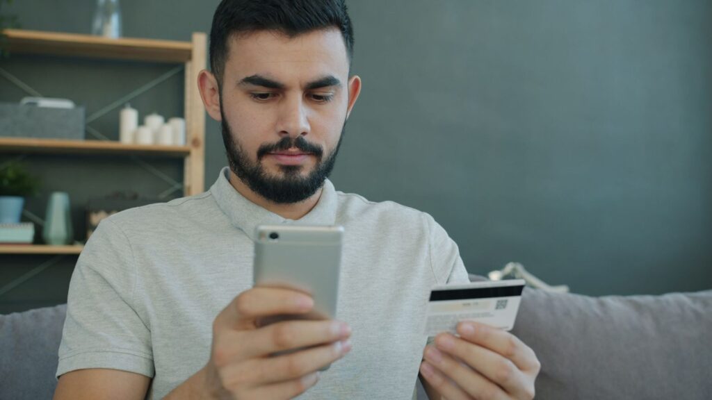 Persona verificando su identidad con el móvil y una tarjeta, como en el KYC de un cajero de Bitcoin
