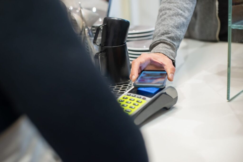 Cliente pagando con el móvil en el datáfono de un comercio: dónde aceptan bitcoin en España