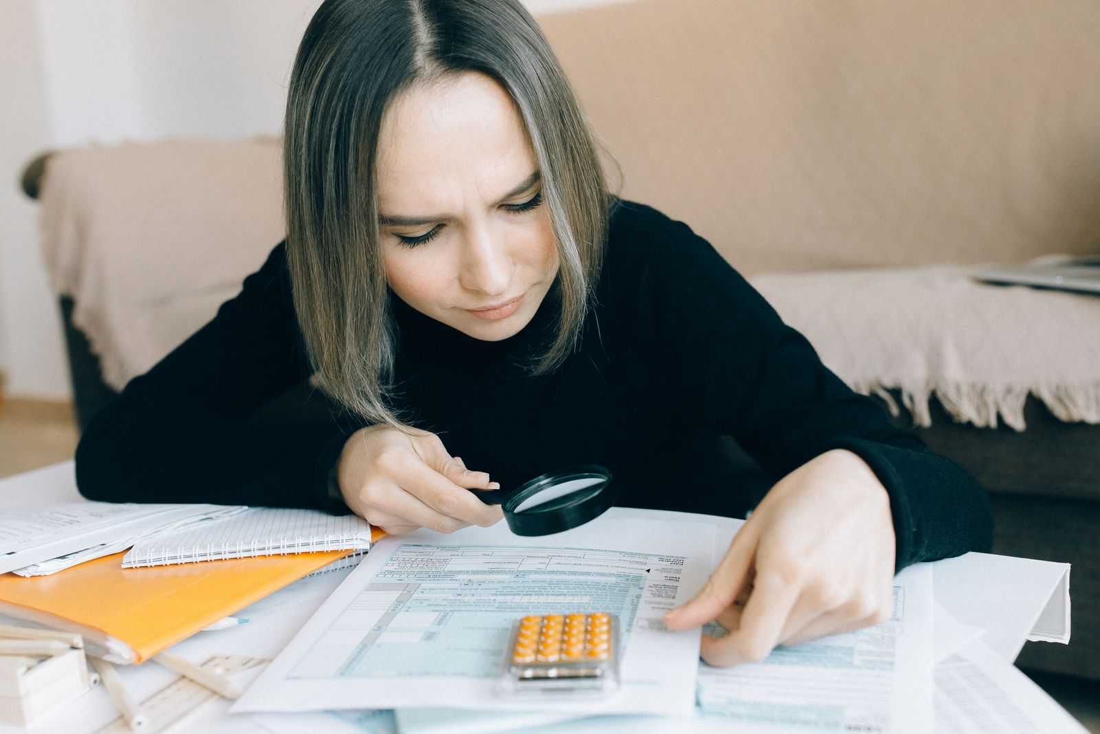 Mujer revisando documentos con una lupa: comprobar si una empresa de criptomonedas está autorizada por la CNMV