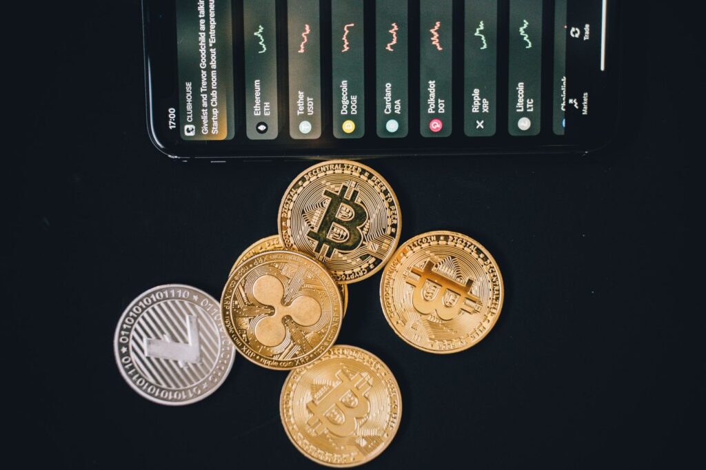 Monedas de criptomonedas junto a un móvil con gráficos: transferencias sujetas a la regla de viaje