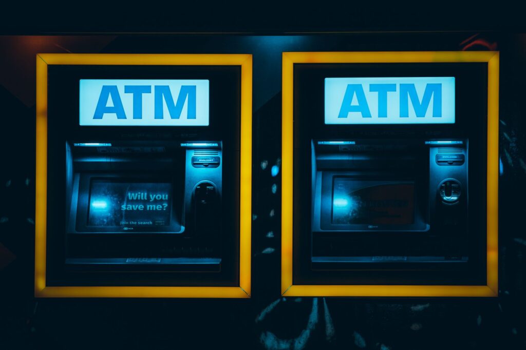 Dos cajeros automáticos iluminados en una calle de noche
