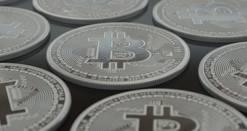 Varias monedas plateadas con el símbolo de bitcoin sobre una superficie oscura