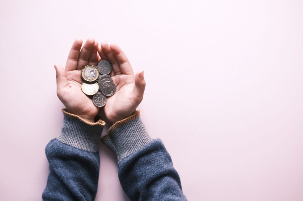 Dos manos juntas sujetando unas pocas monedas pequeñas